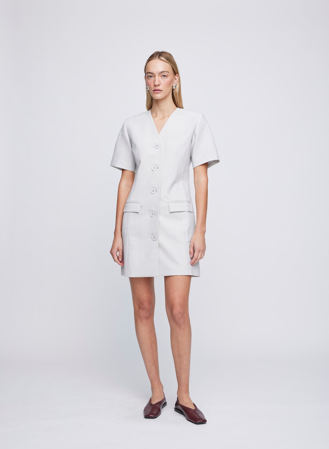 The ANNA QUAN Romy Dress features feminine seam work that shapes the waist line, a v cut neckline and flap pockets. Finishing touches include a button down front and A-line hem. Fully lined for ease of wear and crafted in heather wool suiting. 