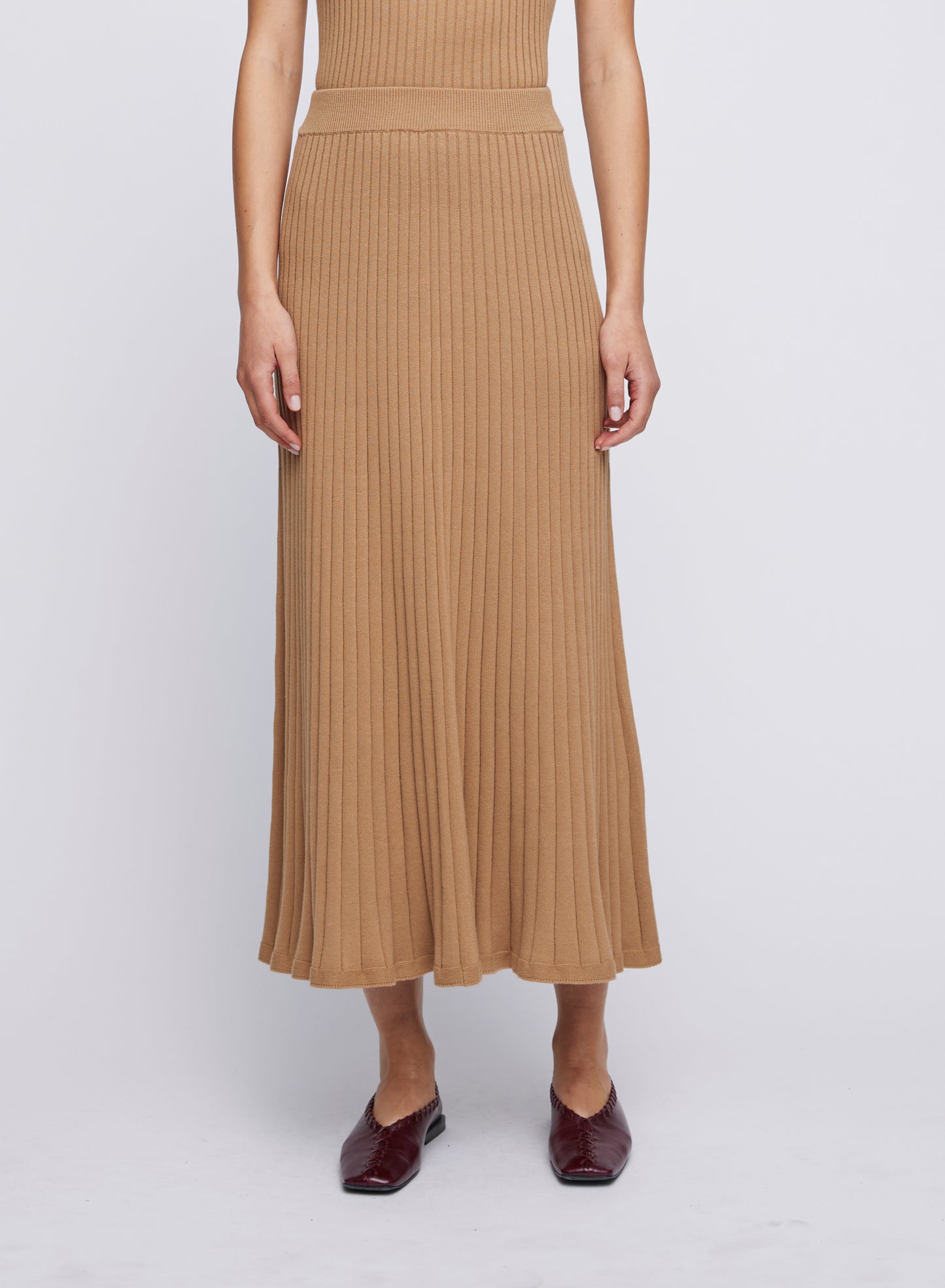 Elevate your wardrobe with ANNA QUAN'S Cotton Rib Midi Skirt featuring a flared hem in the enchanting shade of Macchiato. This midi skirt effortlessly transitions from everyday casual chic to sophisticated elegance, making it a versatile wardrobe essential. Midi knit skirt, everyday knit skirt, everyday midi skirt, work skirts, everyday work skirt, long work skirts, conservative work skirts.