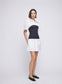 ANNA QUAN's unique Soft Tailoring Mini White Shirt Dress, featuring a contrast jersey rib column skirt. This chic fusion of elements combines the timeless appeal of a white shirt with a modern twist in the torso. White shirt dress, cotton shirt dress, mixed media dress, every day dress, elevated every day dress.